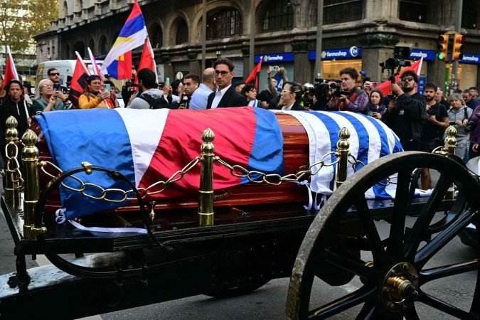 People applaud as the carriage carrying the remains of the late Uruguay's former president (2010-2015) Jose 'Pepe' Mujica moves forward during the funeral cortege in Montevideo, on May 14, 2025. Mujica, an ex-guerrilla fighter and hero of the Latin American left, died on May 13, 2025 at the age of 89. The humble leader -- who once spent a dozen years behind bars for revolutionary activity -- lost his battle against cancer after announcing in January the disease had spread and he would stop treatment. (Photo by Pablo PORCIUNCULA / AFP)
- (crédito: AFP) People applaud as the carriage carrying the remains of the late Uruguay's former president (2010-2015) Jose 'Pepe' Mujica moves forward during the funeral cortege in Montevideo, on May 14, 2025. Mujica, an ex-guerrilla fighter and hero of the Latin American left, died on May 13, 2025 at the age of 89. The humble leader -- who once spent a dozen years behind bars for revolutionary activity -- lost his battle against cancer after announcing in January the disease had spread and he would stop treatment. (Photo by Pablo PORCIUNCULA / AFP)
- (crédito: AFP)