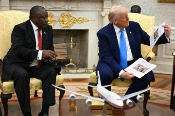 O presidente dos EUA, Donald Trump, mostra fotos e artigos enquanto se encontra com o presidente sul-africano, Cyril Ramaphosa -  (crédito: Foto: Jim WATSON/AFP)