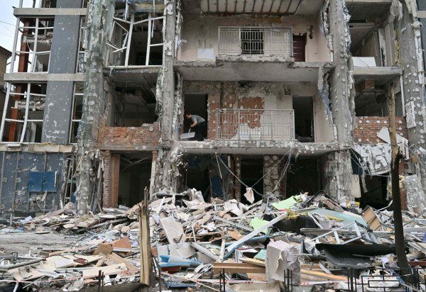 Morador limpa os escombros do apartamento destruído após um ataque de drone em Kiev, em 25 de maio de 2025       -  (crédito: Sergei SUPINSKY/AFP)