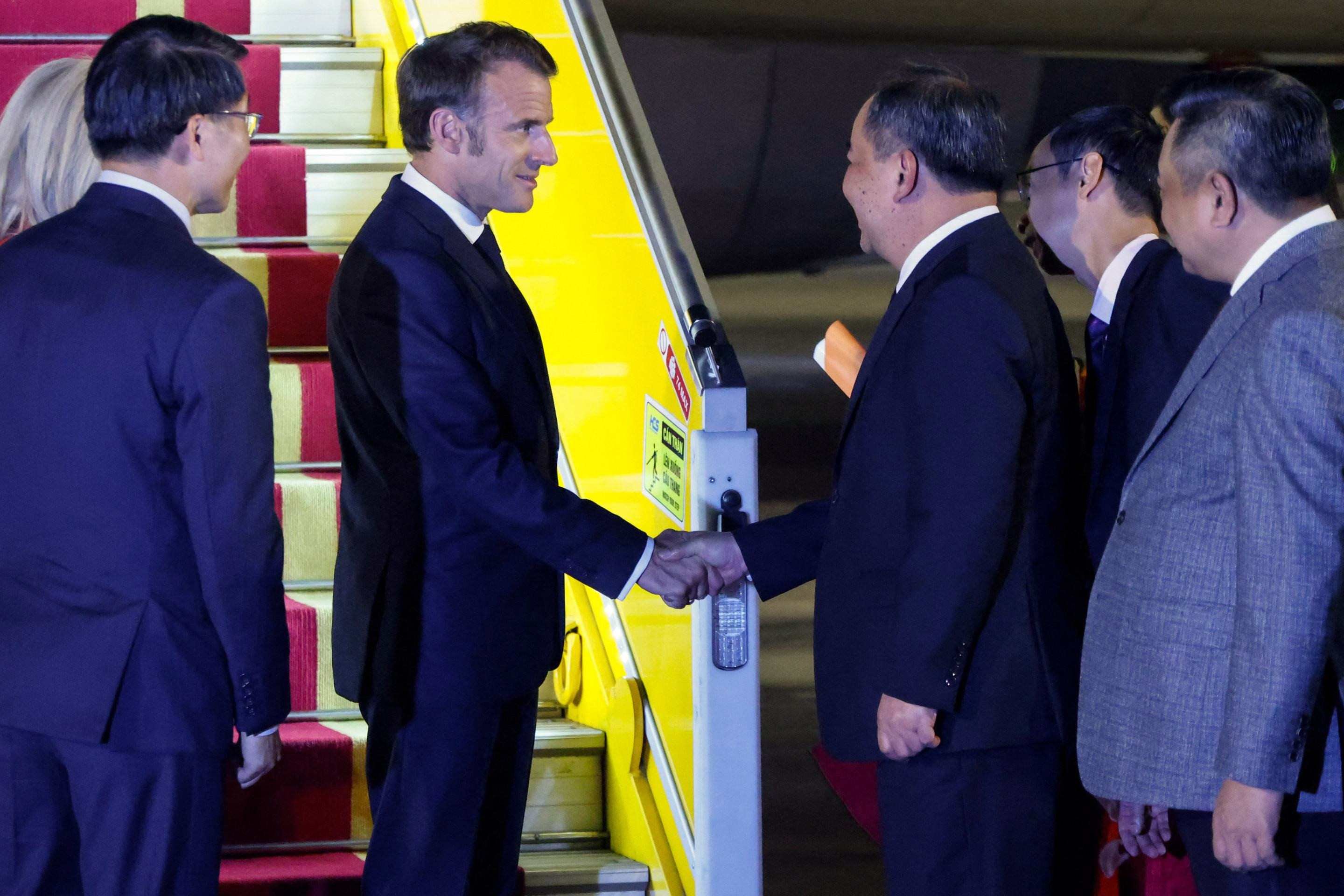  Frances President Emmanuel Macron (C) shakes hands with Vietnamese officials upon his arrival at Noi Bai International Airport in Hanoi on May 25, 2025. French President Emmanuel Macron arrived in Hanoi on May 25, an AFP journalist saw, for the first leg of a Southeast Asia tour that will also see him travel to Indonesia and Singapore. (Photo by Ludovic MARIN / AFP)       