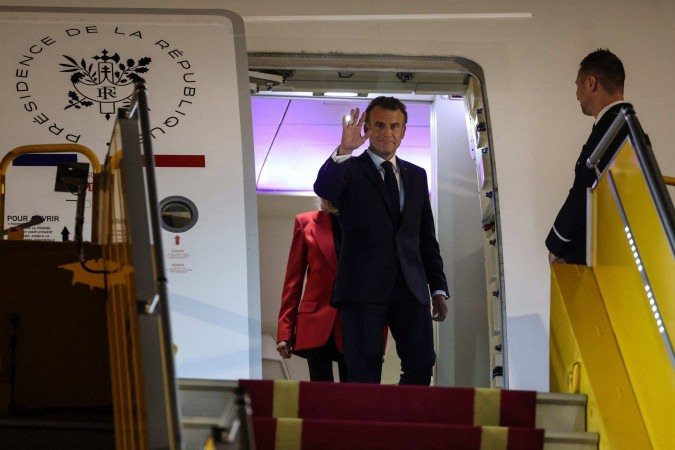 Visivelmente surpreso, o presidente rapidamente se volta para a imprensa e acena, tentando retomar a compostura -  (crédito:  Ludovic MARIN / AFP)