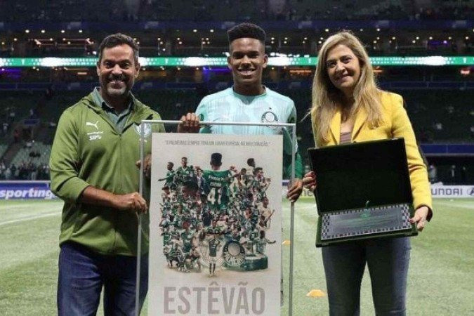 Estêvão recebe uma placa das mãos da presidente Leila Pereira - (crédito: Foto: Divulgação/Palmeiras) Estêvão recebe uma placa das mãos da presidente Leila Pereira - (crédito: Foto: Divulgação/Palmeiras)