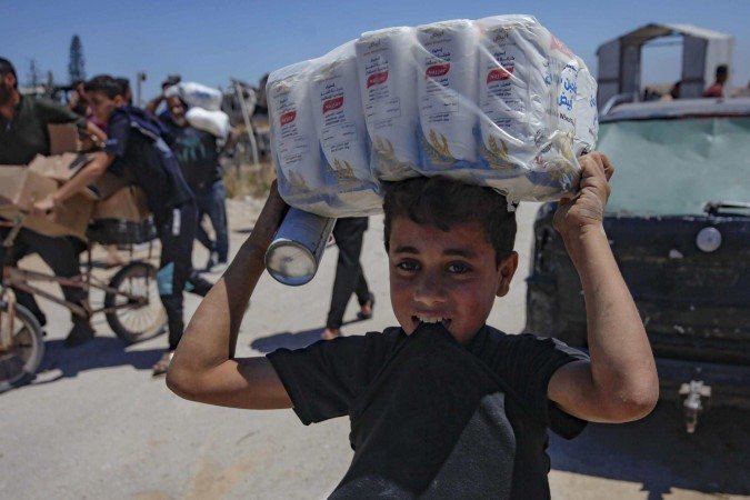 Imagens mostram homem fazendo sinal de coração para os moradores de Gaza em um centro de distribuição. Ao fundo, a cerca pode ser vista cedendo aos empurrões -  (crédito: Telegram)