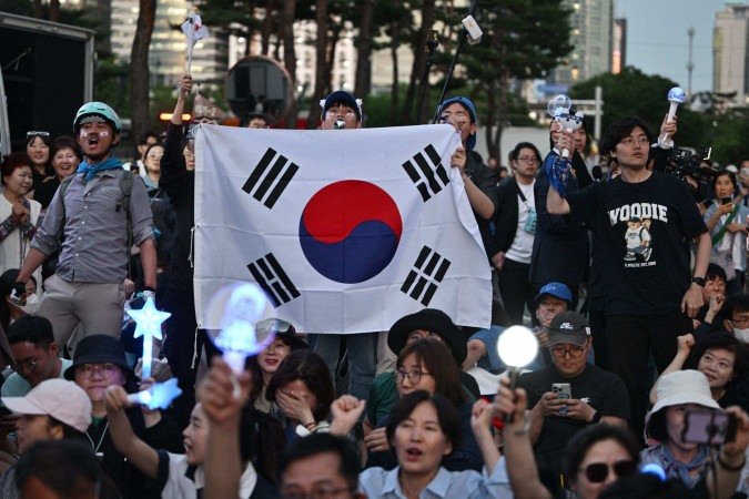 Pessoas comemoram após pesquisas de boca de urna mostrarem que Lee Jae-myung, do Partido Democrata de esquerda, da Coreia do Sul, parece estar a caminho de vencer a eleição presidencial em Seul, em 3 de junho de 2025       -  (crédito: ANTHONY WALLACE/AFP)