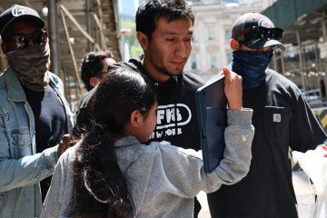 Menina tenta abraçar o pai, ao ser escoltada por agentes federais, após audiência no Programa Intensivo de Supervisão de Comparecimento do ICE, em Nova York  -  (crédito: Michael M. Santiago/Getty Images/AFP)
