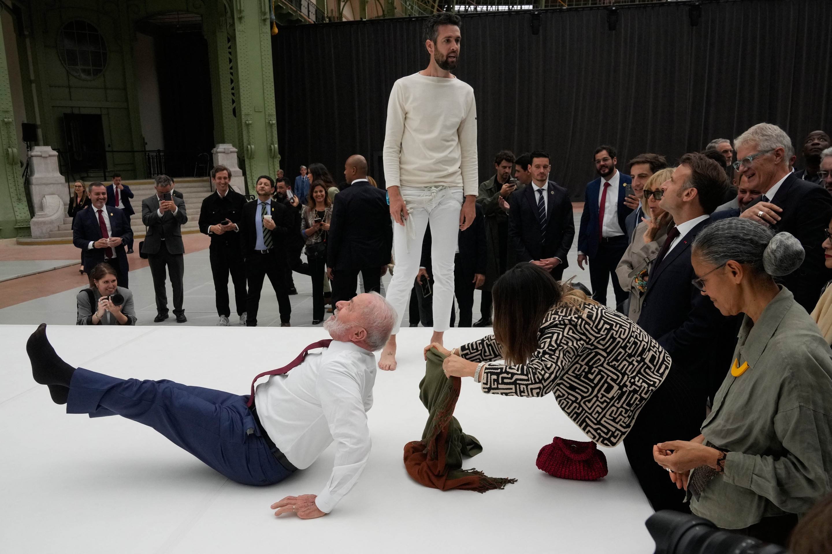 O presidente brasileiro Luiz Inácio Lula da Silva tenta reproduzir um movimento de acrobatas durante visita a uma exposição como parte de sua visita de Estado à França, em 6 de junho de 2025  