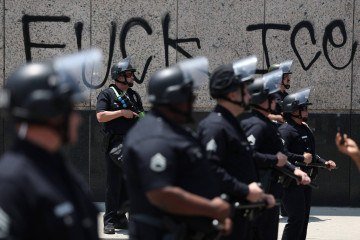 Forças de segurança diante de muro com a frase 'F..., ICE', em referência à polícia da Imigração
 -  (crédito: Patrick T. Fallon/AFP)