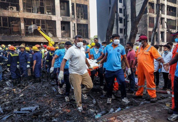 Rescue officials carry a victim's body at the site where Air India flight 171 crashed in a residential area near the airport in Ahmedabad on June 12, 2025. A London-bound enger plane crashed in the Indian city of Ahmedabad on June 12 and all 242 people on board were believed killed, with the jet smashing into buildings housing doctors and their families. (Photo by Sam PANTHAKY / AFP)
- (crédito: AFP)
