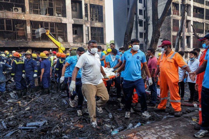  Rescue officials carry a victim's body at the site where Air India flight 171 crashed in a residential area near the airport in Ahmedabad on June 12, 2025. A London-bound passenger plane crashed in the Indian city of Ahmedabad on June 12 and all 242 people on board were believed killed, with the jet smashing into buildings housing doctors and their families. (Photo by Sam PANTHAKY / AFP)
      