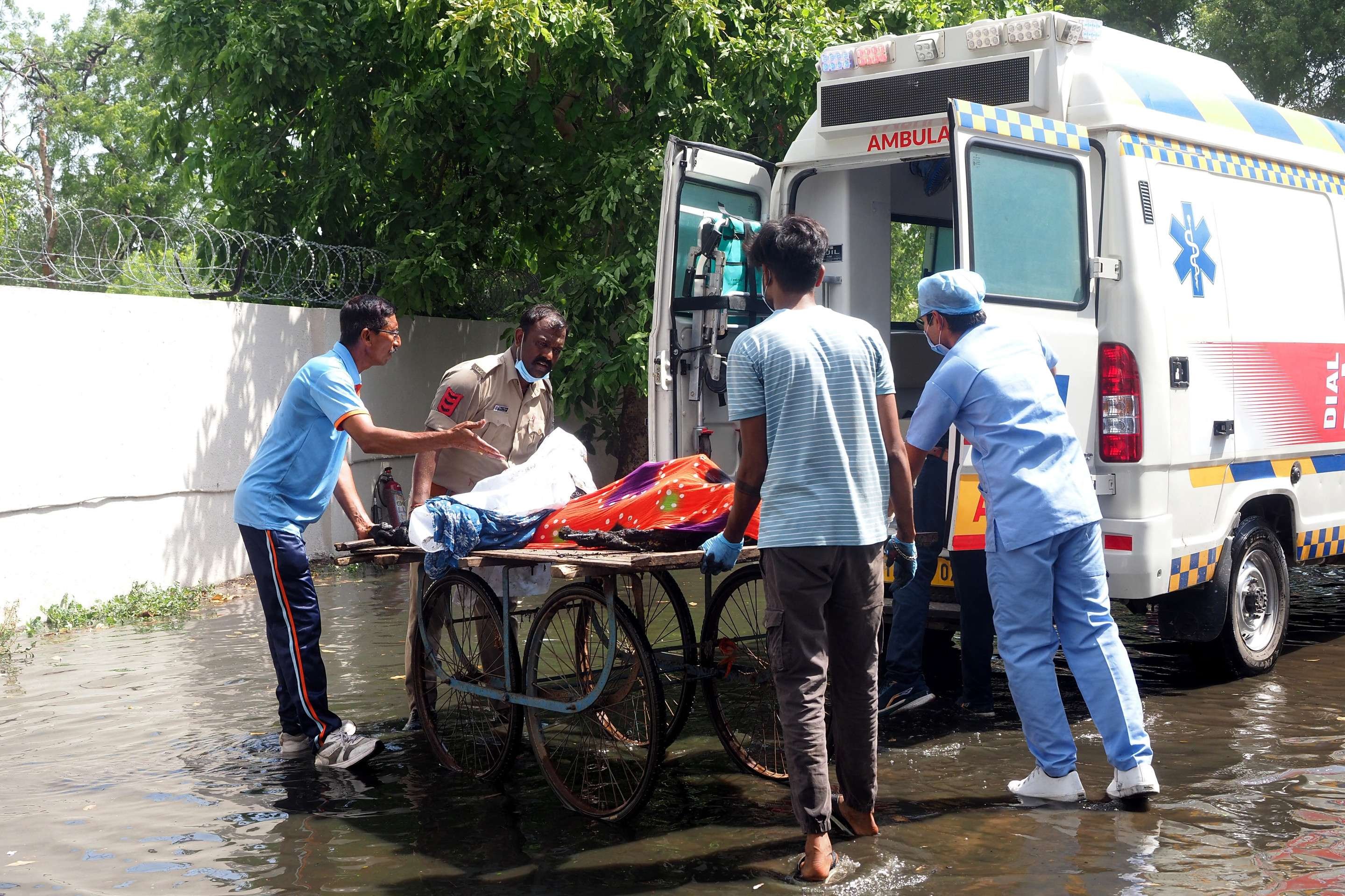 Um policial e médicos transferem corpos de vítimas para uma ambulância após o voo 171 da Air India cair em uma área residencial perto do aeroporto de Ahmedabad, em 12 de junho de 2025      