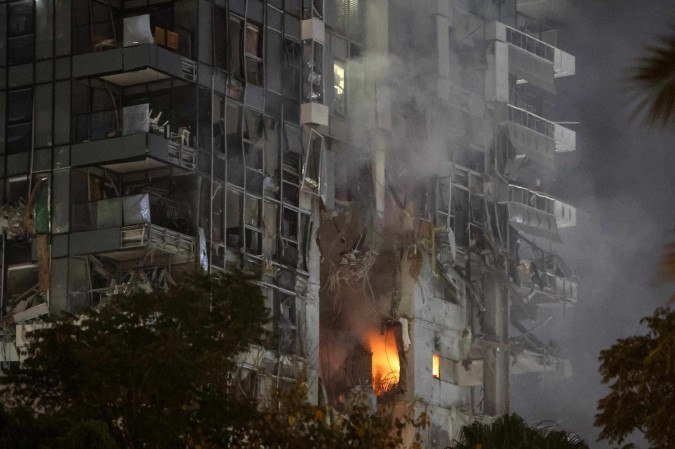Fogo e fumaça sobem de edifício impactado por míssil, no centro de Tel Aviv - (crédito: Jack Guez/AFP) Fogo e fumaça sobem de edifício impactado por míssil, no centro de Tel Aviv - (crédito: Jack Guez/AFP)