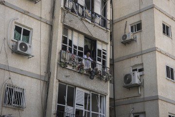  A man looks out from his damaged balcony at a site in Tel Aviv hit by a missile fired from Iran on June 14, 2025. Israel's military said that its fighter jets were set to resume striking targets in Tehran, after announcing it had hit air defences in the Iranian capital area overnight, as Israel and Iran trade fire with such intensity for the first time following decades of enmity and conflict by proxy, with fears of a prolonged conflict engulfing the region. (Photo by JOHN WESSELS / AFP)
      Caption 