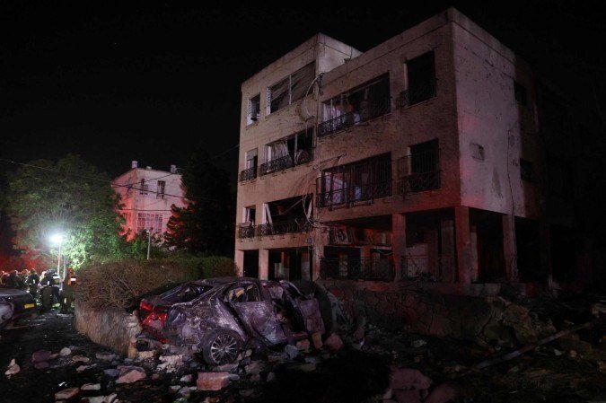 Israeli emergency and security service members deploy at a site hit by an Iranian rocket in the city of Haifa on June 15, 2025. Israel and Iran traded heavy fire for a third straight day on June 15, with mounting casualties and expanding targets marking a sharp escalation in hostilities between the longtime foes. (Photo by AHMAD GHARABLI / AFP)
- (crédito: AFP) Israeli emergency and security service members deploy at a site hit by an Iranian rocket in the city of Haifa on June 15, 2025. Israel and Iran traded heavy fire for a third straight day on June 15, with mounting casualties and expanding targets marking a sharp escalation in hostilities between the longtime foes. (Photo by AHMAD GHARABLI / AFP)
- (crédito: AFP)