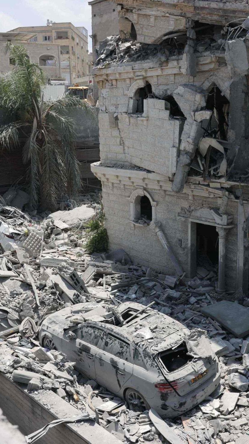 Carros danificados jazem em meio aos escombros de um prédio danificado na cidade de Tamra, no norte de Israel, após um ataque de míssil do Irã durante a noite de 15 de junho de 2025 
       -  (crédito: Ahmad Gharabili/AFP)