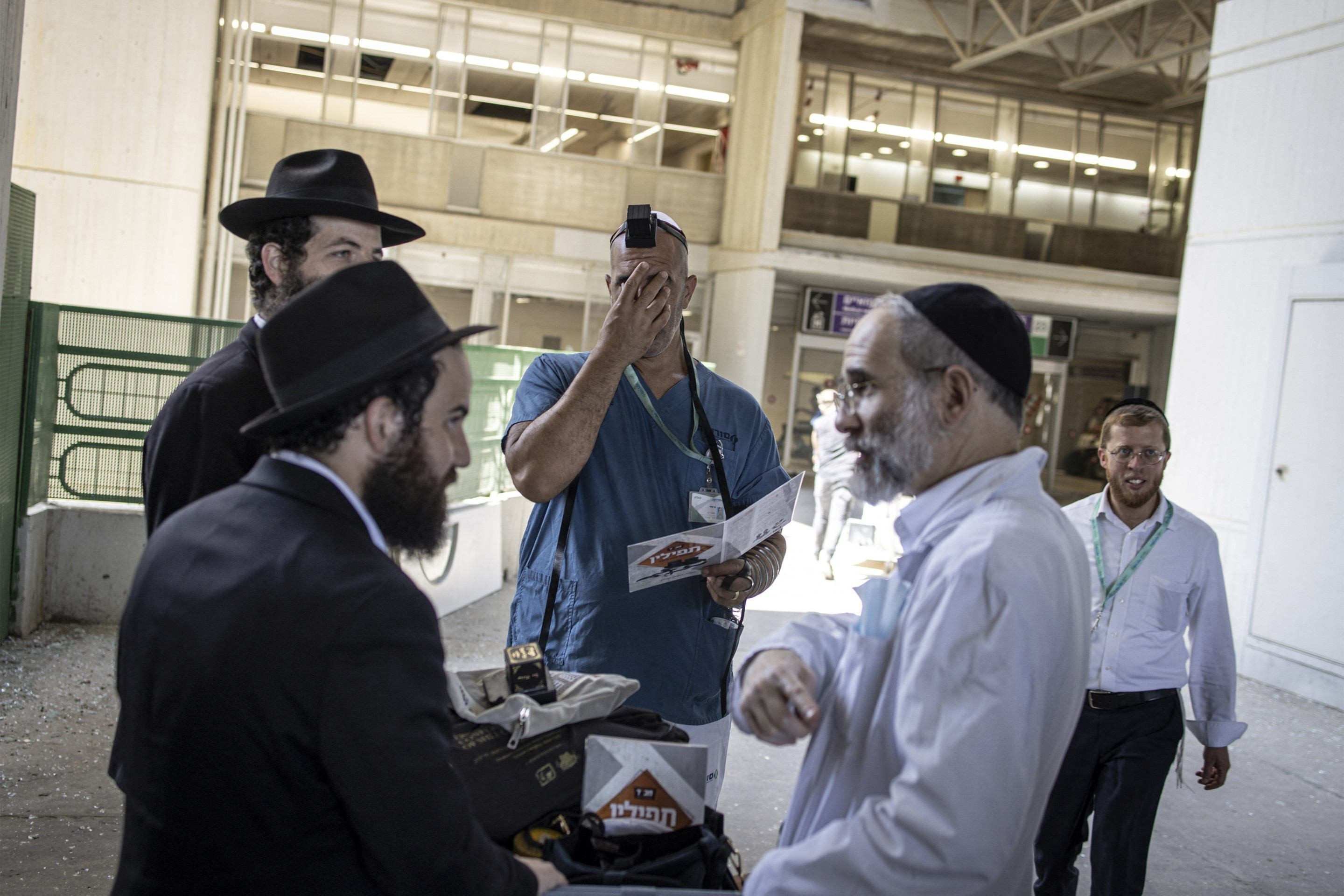 Um médico faz uma oração com o Torá na mão, apoós ataque ao hospital Soroka, em Beersheba, no sul de Israel, na manhã desta quinta-feira (19/6) 