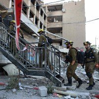 Socorristas israelenses entram em prédio atingido por míssil iraniano, na cidade portuária de Haifa (norte)  -  (crédito: Fadel Senna/AFP)