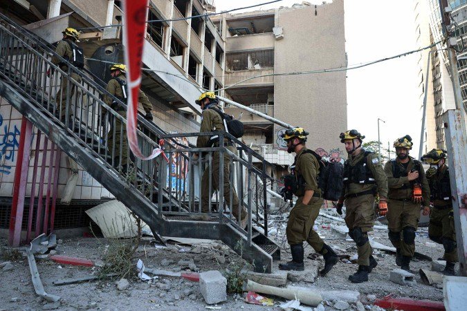 Socorristas israelenses entram em prédio atingido por míssil iraniano, na cidade portuária de Haifa (norte) - (crédito: Fadel Senna/AFP) Socorristas israelenses entram em prédio atingido por míssil iraniano, na cidade portuária de Haifa (norte) - (crédito: Fadel Senna/AFP)
