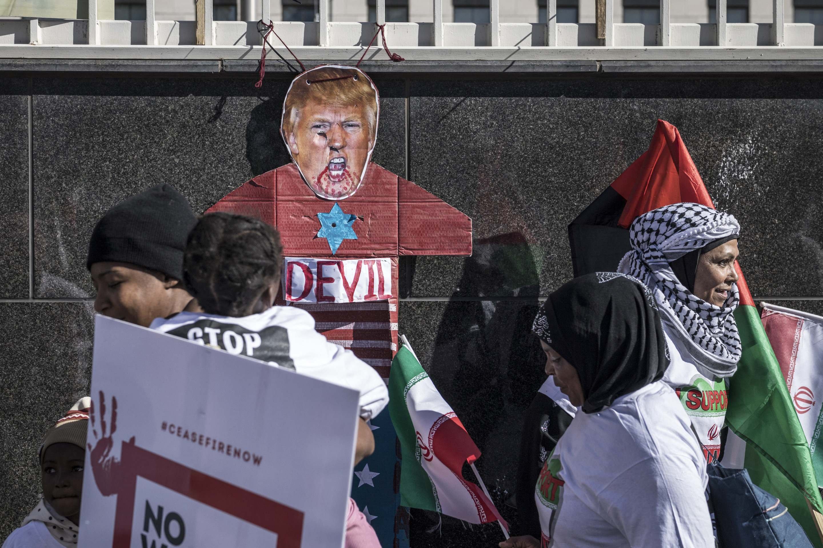 Um recorte representando o presidente dos EUA, Donald Trump, é amarrado a uma parede enquanto manifestantes se reúnem em frente ao Consulado dos EUA durante um protesto contra a guerra em curso entre Israel e o Irã e para expressar solidariedade à população da Faixa de Gaza, em Joanesburgo, em 21 de junho de 2025. (Foto de MARCO LONGARI / AFP)