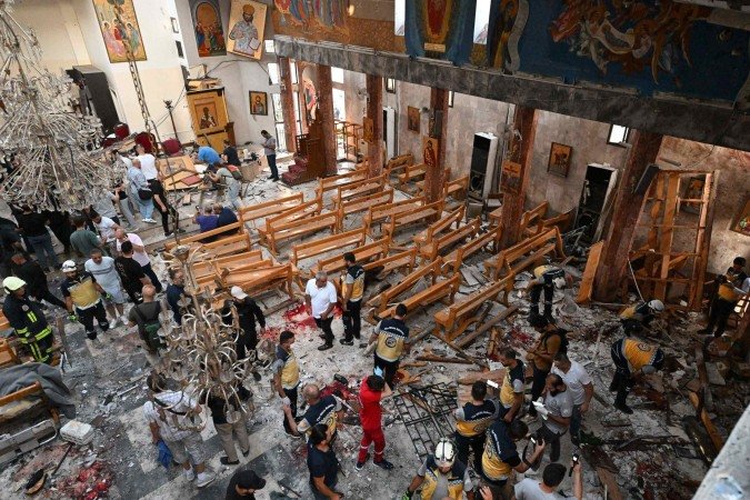 Pessoas e equipes de resgate inspecionam os danos no local de um suposto ataque suicida na igreja de Santo Elias, na área de Dwelaa, em Damasco, em 22 de junho de 2025. A mídia estatal síria noticiou um ataque suicida contra uma igreja de Damasco em 22 de junho, que deixou vítimas. -  (crédito: Photo by LOUAI BESHARA / AFP)