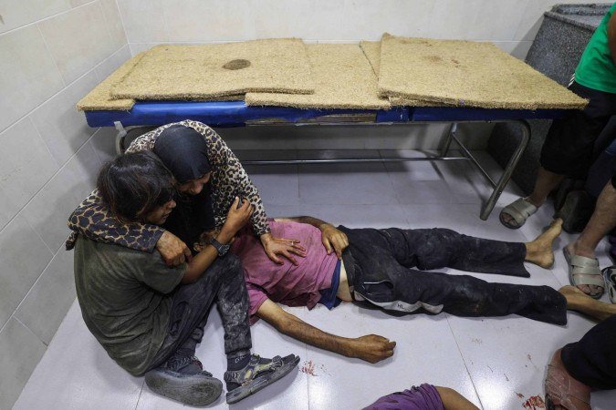 Palestinos com familiar morto na fila de distribuição de ajuda, em Gaza: o sofrimento parece ter sido normalizado - (crédito: Eyad Baba/AFP) Palestinos com familiar morto na fila de distribuição de ajuda, em Gaza: o sofrimento parece ter sido normalizado - (crédito: Eyad Baba/AFP)