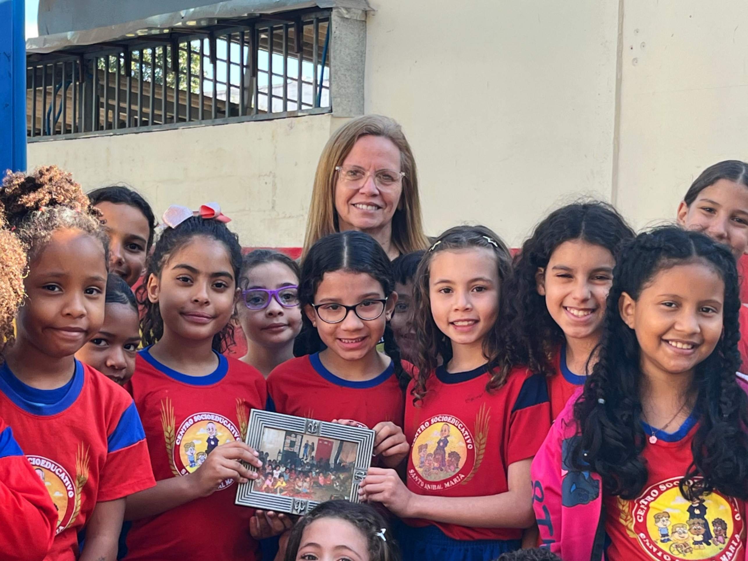 Dione Gaudino e algumas das crian&ccedil;as do Santo An&iacute;bal segurando um retrato da primeira sala do centro, h&aacute; mais de uma d&eacute;cada