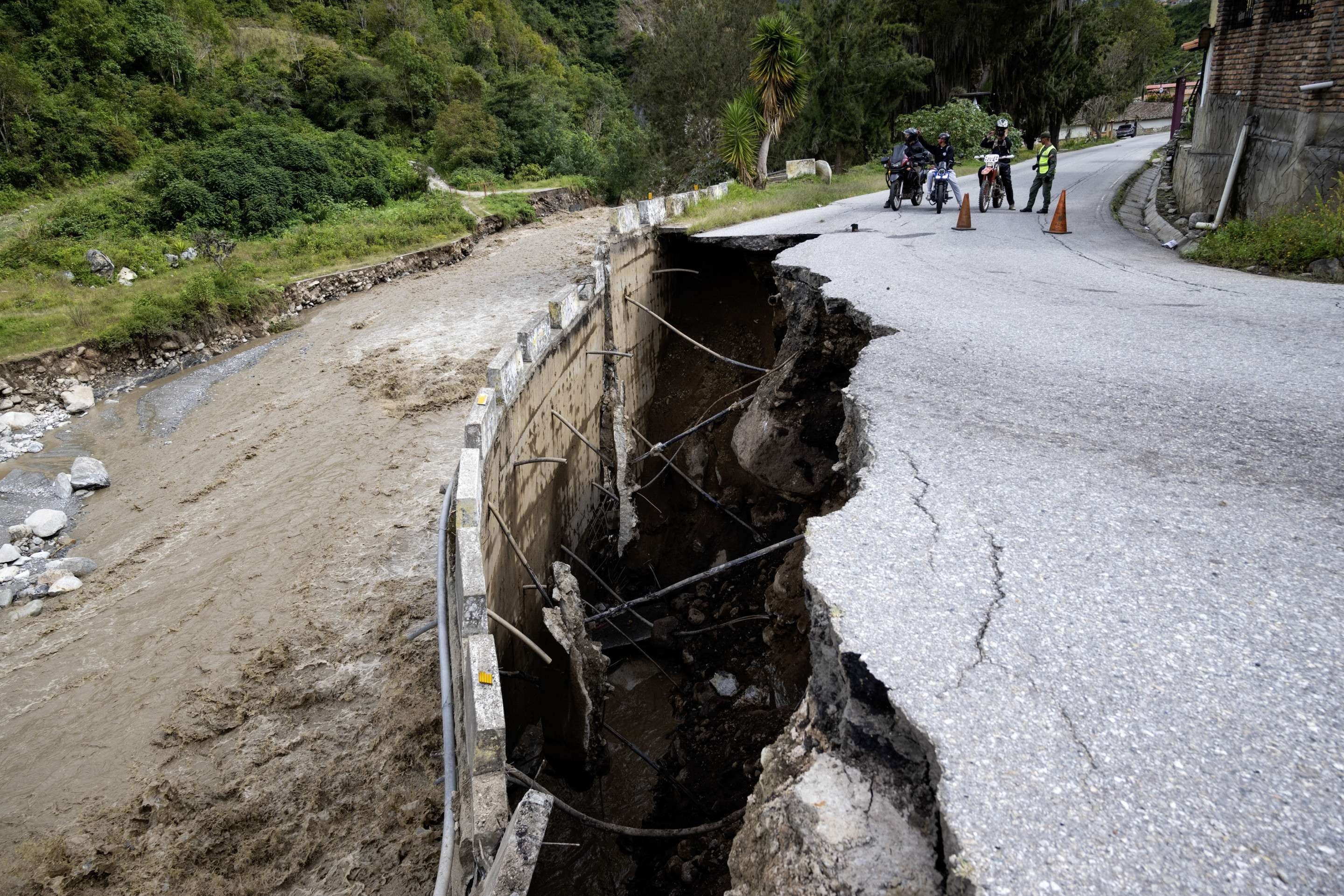 Motociclistas parados na Rodovia Trasandina, parcialmente destruída pela enchente do rio Chama, perto de Mérida, estado de Mérida, oeste da Venezuela, em 25 de junho de 2025, após fortes chuvas na região      