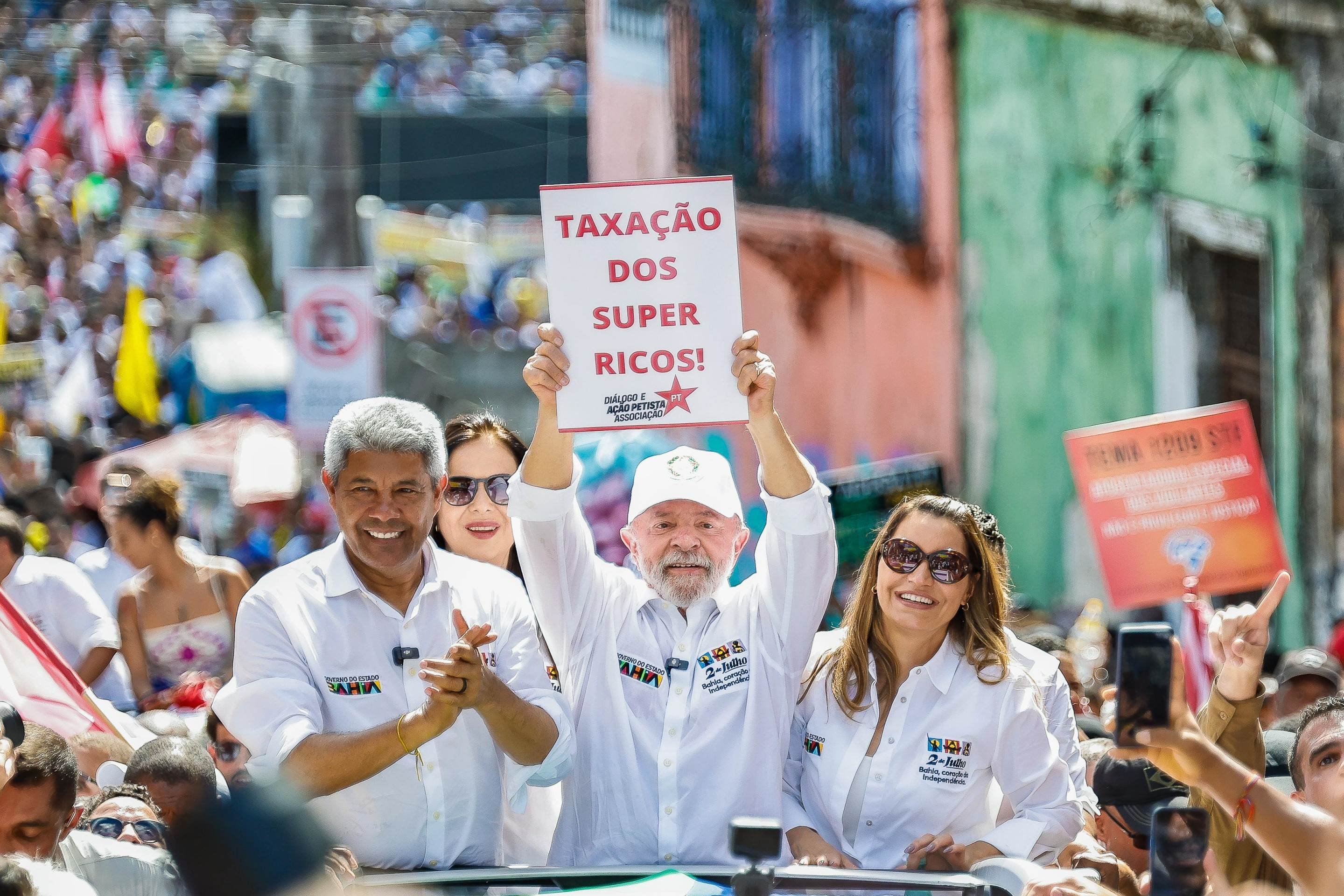 Lula entre Janja e o governador Jerônimo Rodrigues, em Salvador, mostra cartaz defendendo proposta do governo -  (crédito: Ricardo Stuckert/PR)