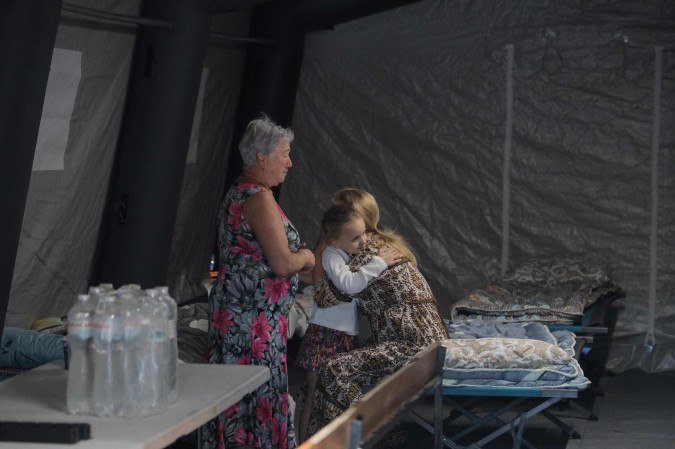 Garota ucraniana recebe abraço em tenda para moradia provisória, após ataque ao prédio onde vivia, em Odessa - (crédito: Oleksandr Gimanov/AFP) Garota ucraniana recebe abraço em tenda para moradia provisória, após ataque ao prédio onde vivia, em Odessa - (crédito: Oleksandr Gimanov/AFP)