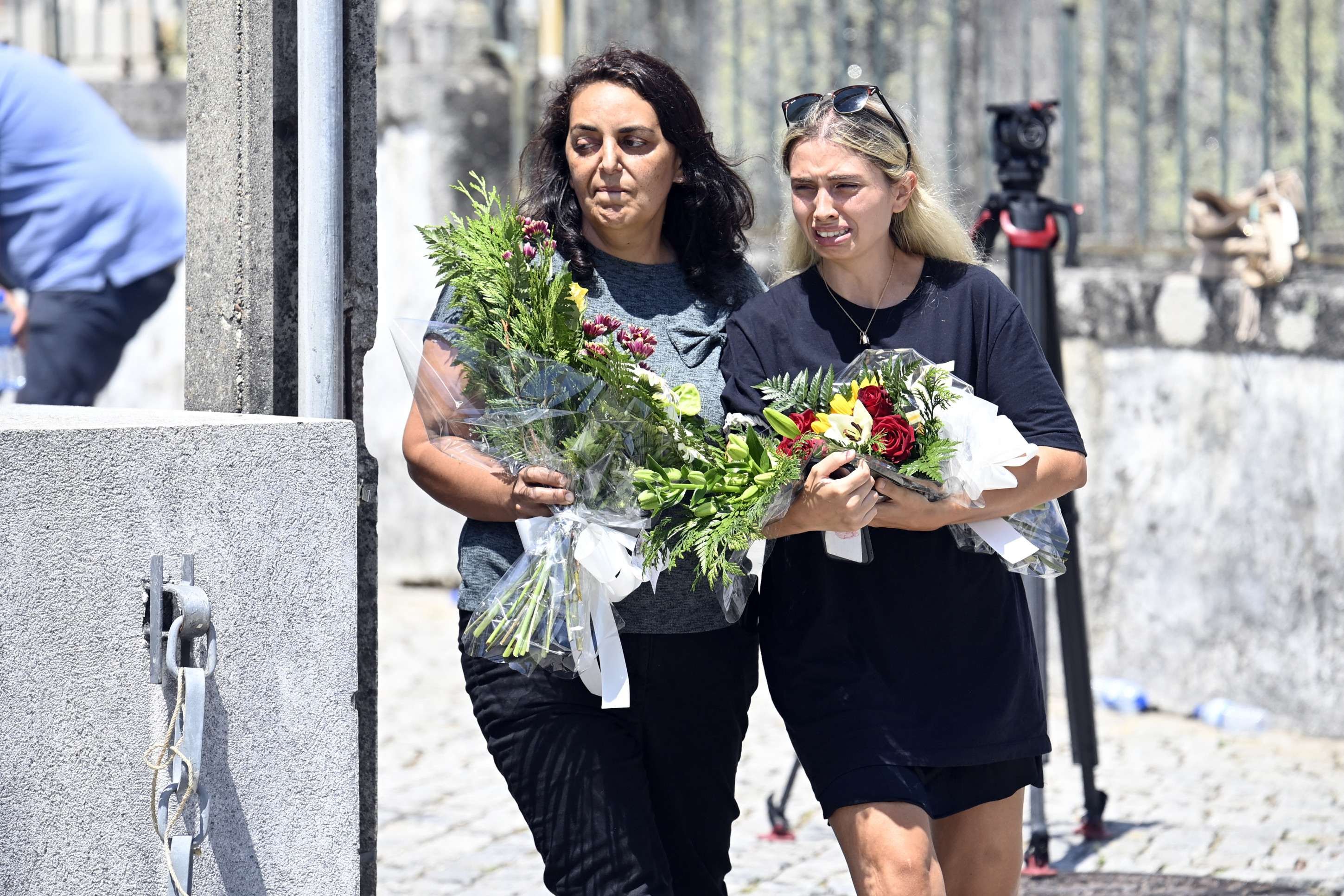 Duas mulheres carregando flores chegam ao velório do atacante português do Liverpool, Diogo Jota, e de seu irmão, André Silva, em Gondomar, nos arredores do Porto. (Photo by MIGUEL RIOPA / AFP)       