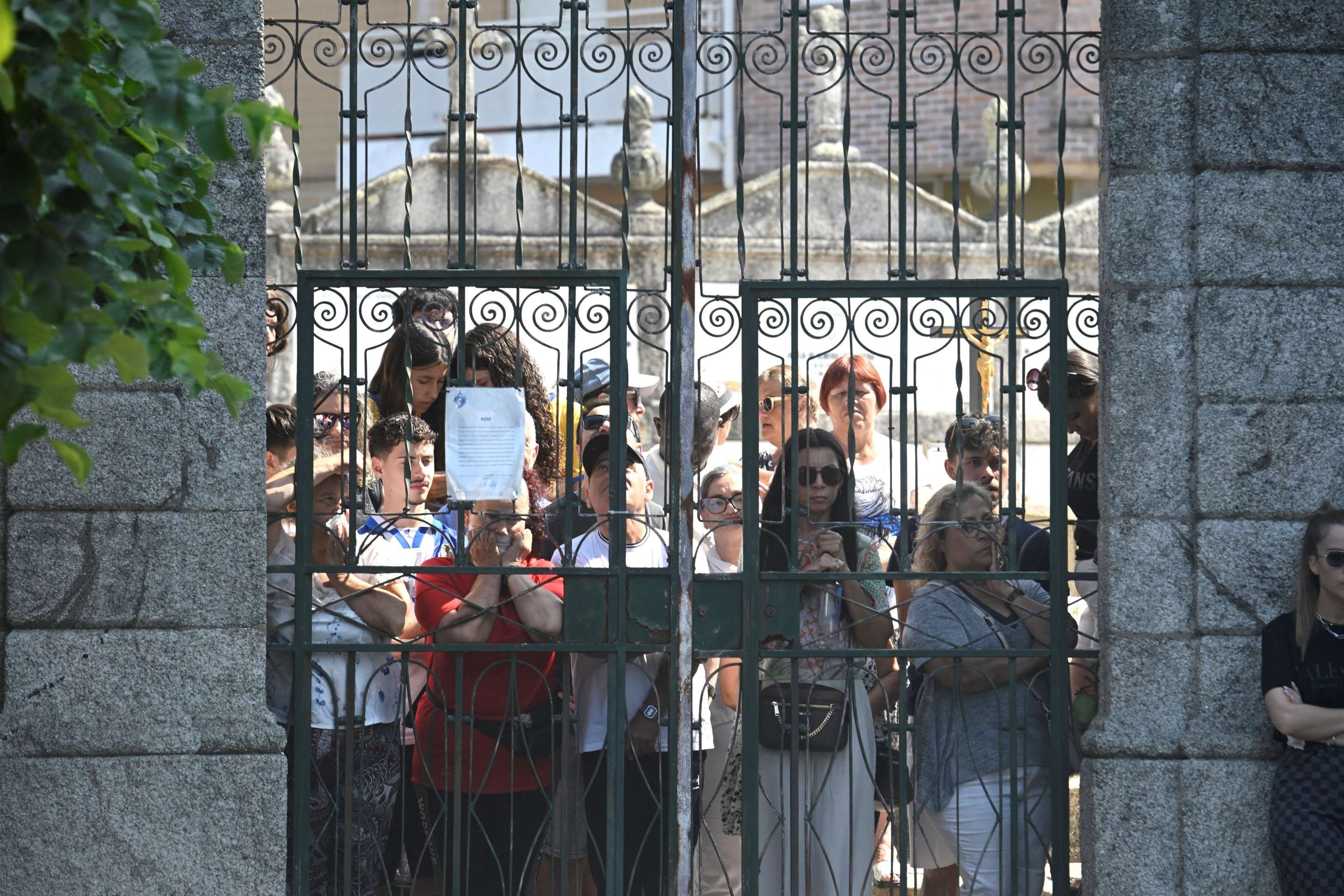  People stand behind the gate of the cemetery during the funeral ceremony of Liverpools Portuguese forward Diogo Jota and his brother Andre Silva in Gondomar, on the outskirts of Porto, on July 5, 2025. Liverpool forward Diogo Jota and his brother died in a car crash in Spain on July 3, 2025, sparking widespread grief just after the Portugal star had got married. (Photo by MIGUEL RIOPA / AFP)       