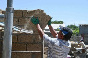 Trabalhadores constroem uma casa com blocos de construção de arroz, feitos principalmente de cascas de arroz - um subproduto do processamento de arroz, na vila de Kyzyl-Kiya, no sul do Quirguistão       -  (crédito: Guliza Urustambek kyzy/AFP)