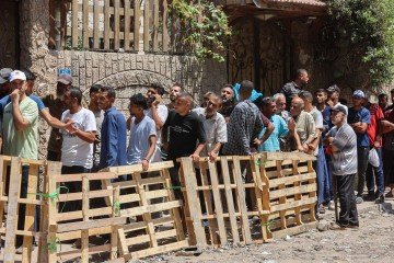 Palestinos fazem fila para retirar um saco de farinha em armazém da ONU   -  (crédito:  AFP)