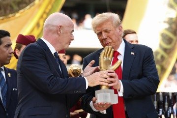 O presidente dos EUA, Donald Trump, olha para o troféu da luva de ouro ao lado do presidente da Fifa, Gianni Infantino, após o Chelsea vencer o PSG na final da Copa do Mundo de Clubes -  (crédito: Kevin Lamarque/POOL/AFP)