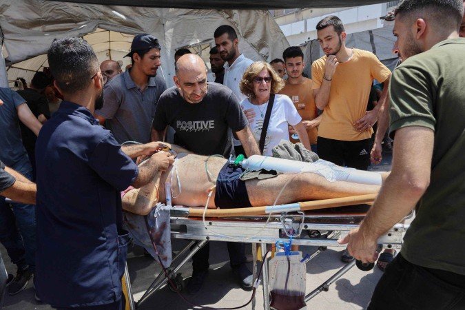 Homem ferido gravemente é levado para tenda do hospital Al Ahli 