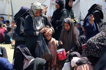 Uma mulher acaricia a cabeça de uma criança enquanto palestinos esperam em um ponto de distribuição de alimentos no campo de refugiados de Nuseirat, no centro da Faixa de Gaza, em 19 de julho de 2025 -  (crédito: Eyad BABA/AFP)