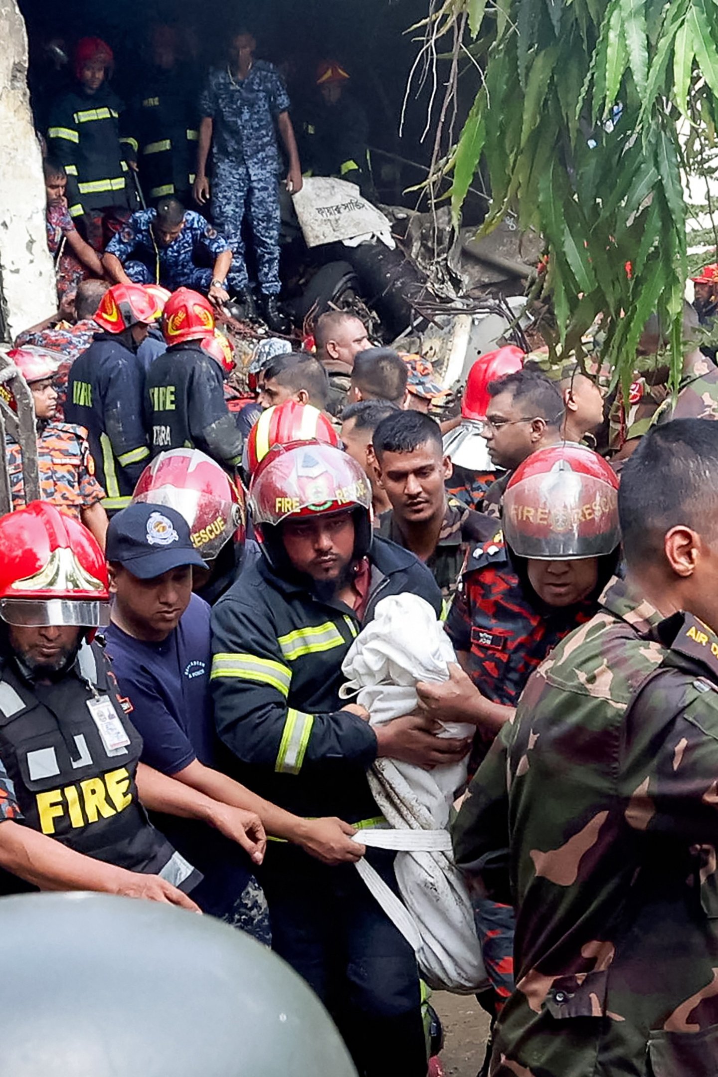  Fire service and army personnel conduct a search and rescue operation after a Bangladesh Air Force training jet crashed into school in Dhaka on July 21, 2025. At least 16 people, mostly students, were killed on July 21, when a training aircraft of the Bangladesh Air Force crashed into a school campus in the capital Dhaka, the government said. (Photo by Abdul Goni / AFP)       