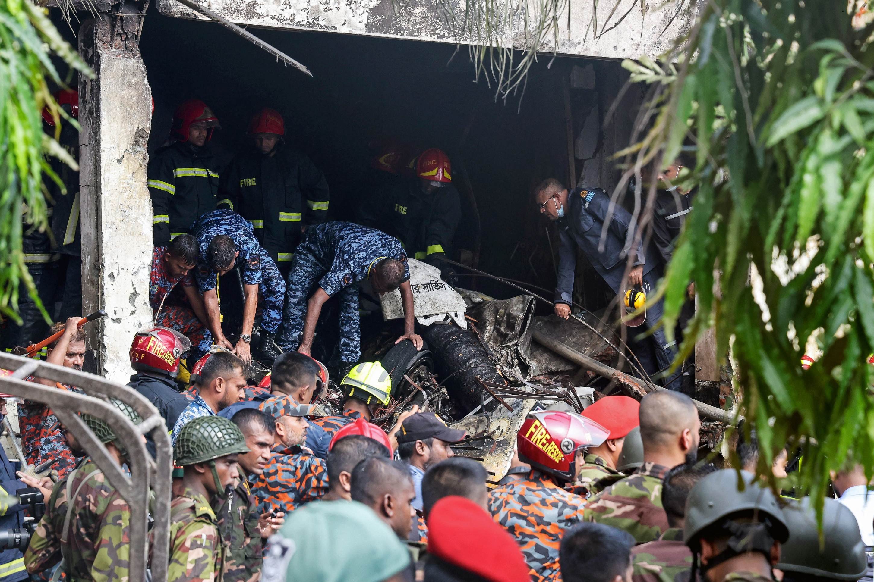  Bangladeshs fire service and security personnel conduct a search and rescue operation after a Air Force training jet crashed into school in Dhaka on July 21, 2025. At least 16 people, mostly students, were killed on July 21, when a training aircraft of the Bangladesh Air Force crashed into a school campus in the capital Dhaka, the government said. (Photo by Abdul Goni / AFP)       