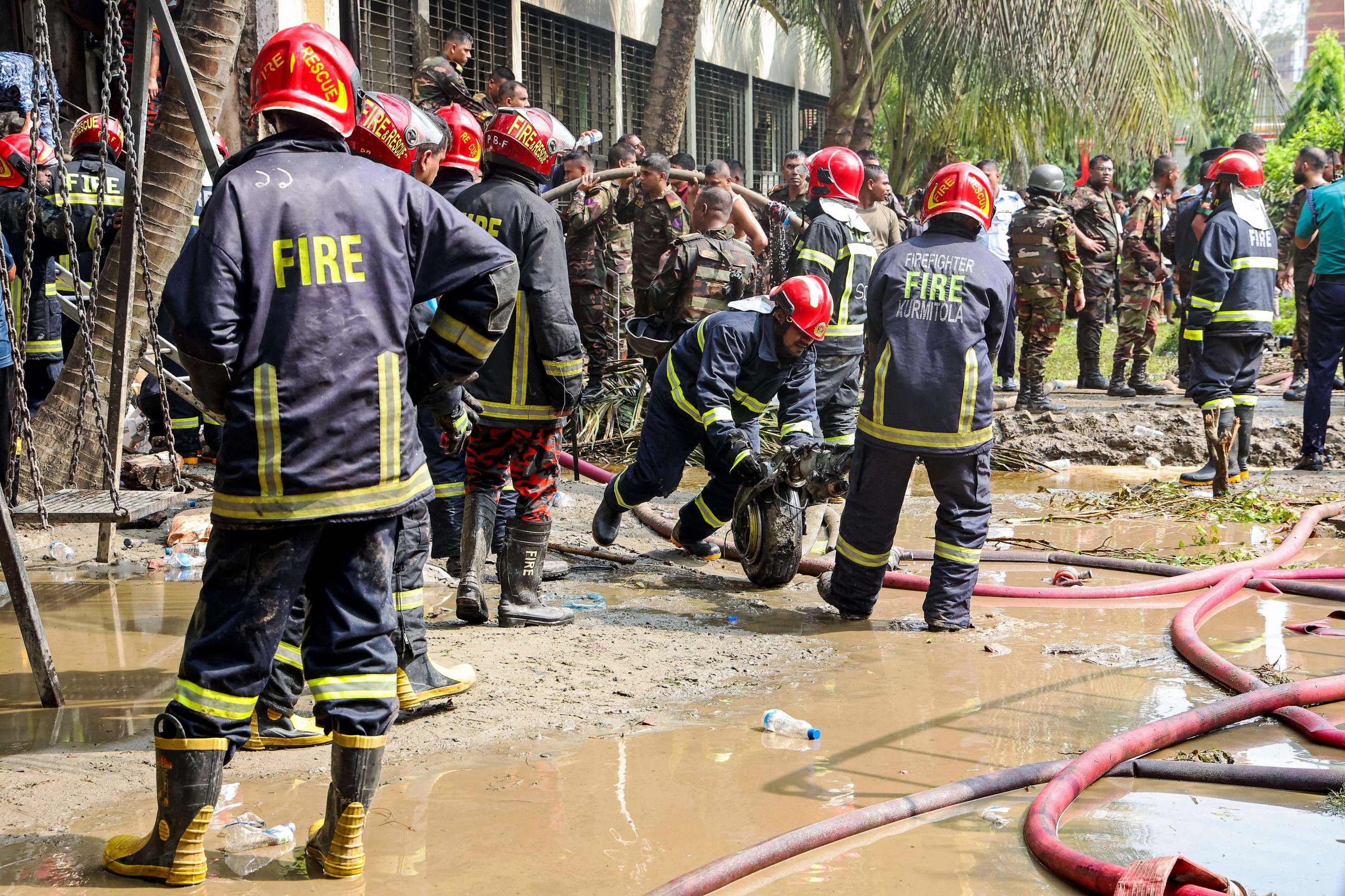  Bangladeshs fire service personnel clear the remains of an Air Force training jet that crashed into a school, during a search and rescue operation in Dhaka on July 21, 2025. At least 16 people, mostly students, were killed on July 21, when a training aircraft of the Bangladesh Air Force crashed into a school campus in the capital Dhaka, the government said. (Photo by Abdul Goni / AFP)       