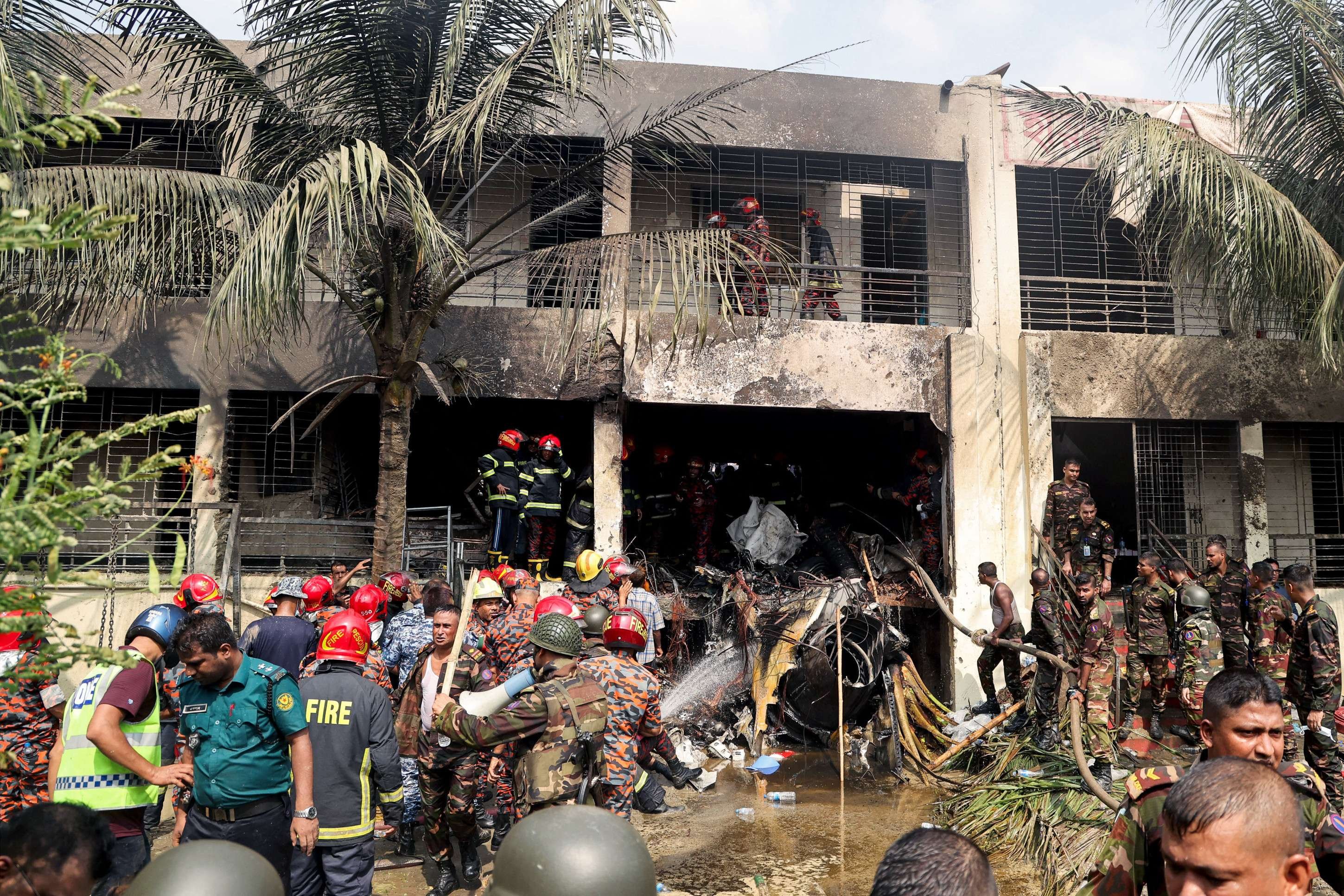  Bangladeshs fire service and security personnel conduct a search and rescue operation after an Air Force training jet crashed into school in Dhaka on July 21, 2025. At least 16 people, mostly students, were killed on July 21, when a training aircraft of the Bangladesh Air Force crashed into a school campus in the capital Dhaka, the government said. (Photo by Abdul Goni / AFP)       