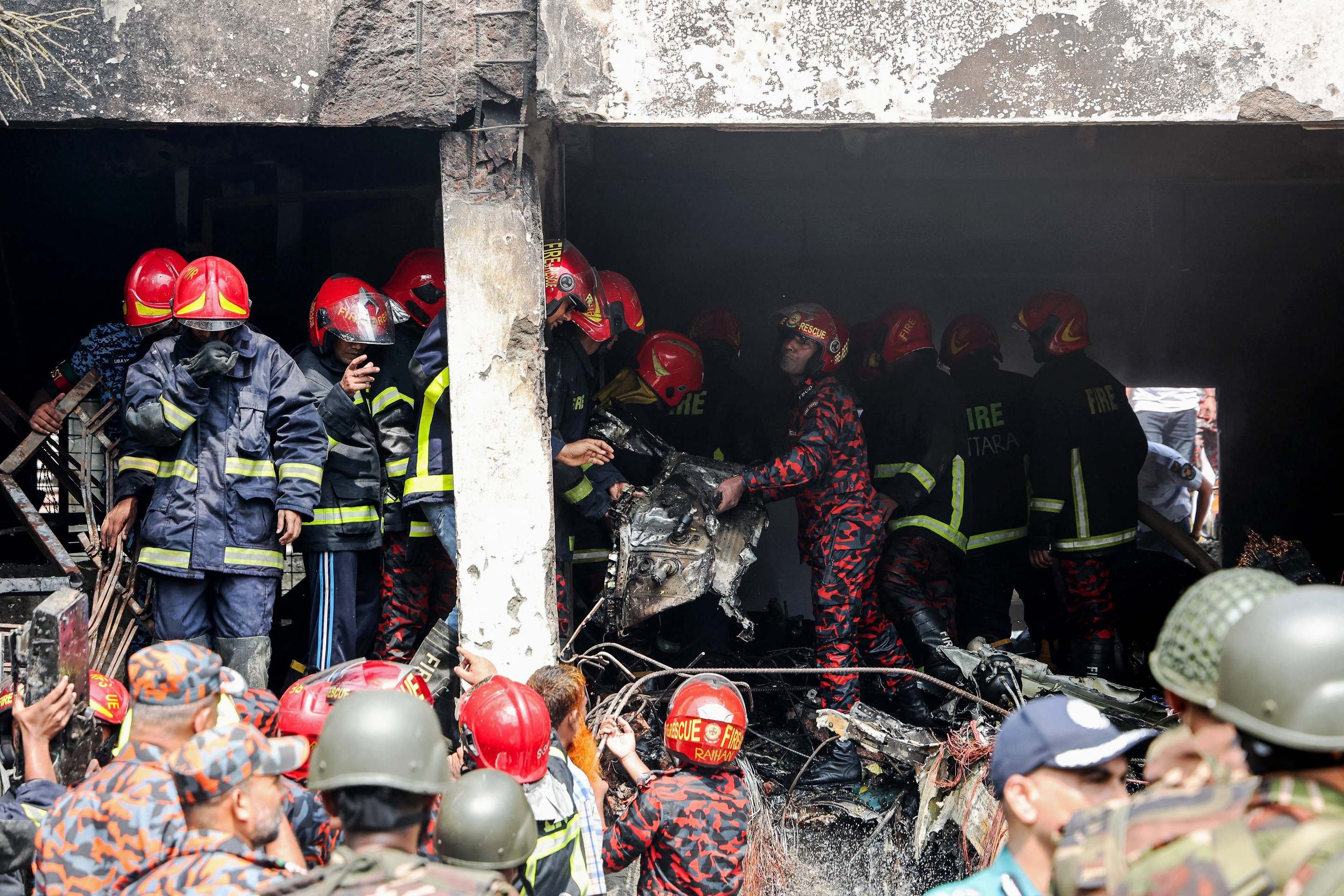  Bangladeshs fire service and security personnel conduct a search and rescue operation as they clear the remains of an Air Force training jet that crashed into a school in Dhaka on July 21, 2025. At least 16 people, mostly students, were killed on July 21, when a training aircraft of the Bangladesh Air Force crashed into a school campus in the capital Dhaka, the government said. (Photo by Abdul Goni / AFP)       
