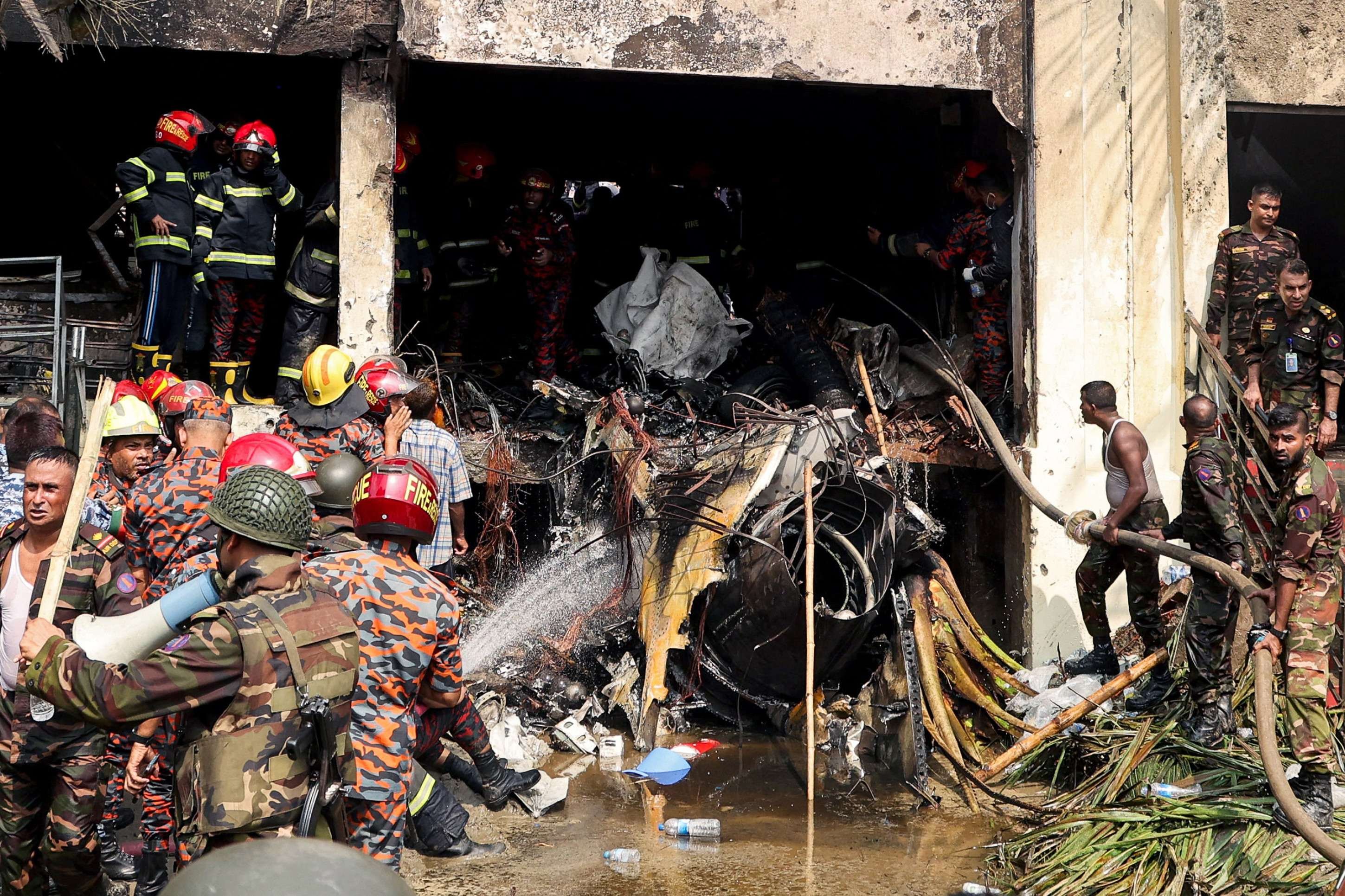  Bangladeshs fire service and security personnel conduct a search and rescue operation after an Air Force training jet crashed into school in Dhaka on July 21, 2025. At least 16 people, mostly students, were killed on July 21, when a training aircraft of the Bangladesh Air Force crashed into a school campus in the capital Dhaka, the government said. (Photo by Abdul Goni / AFP)       