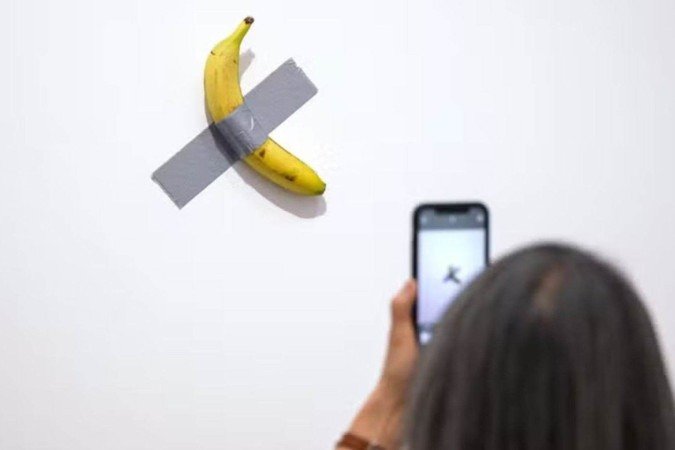 Obra de arte 'Comedian' consiste em uma banana grudada na parede com fita adesiva - (crédito: AFP) Obra de arte 'Comedian' consiste em uma banana grudada na parede com fita adesiva - (crédito: AFP)