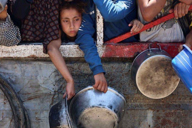 Palestinos tentam pegar pacotes de farinha de um caminhão de ajuda humanitária perto de Zikim, no norte da Faixa de Gaza, em 27 de julho -  (crédito: EPA)