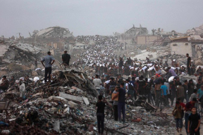 Palestinos carregam pacotes de ajuda humanitária ao caminharem pela zona costeira a oeste de Beit Lahia, no norte de Gaza - (crédito: Omar Al-Qattaa/AFP) Palestinos carregam pacotes de ajuda humanitária ao caminharem pela zona costeira a oeste de Beit Lahia, no norte de Gaza - (crédito: Omar Al-Qattaa/AFP)