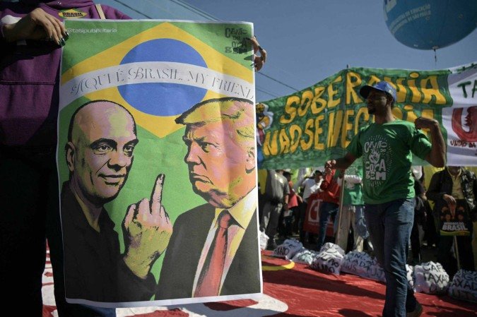  An activist holds a poster depicting Brazil’s Supreme Court Minister Alexandre de Moraes gesturing at US President Donald Trump during a protest in defence of national sovereignty following the US government trade taxes and sanctions on Brazil, near the US consulate, in Sao Paulo, Brazil, on August 1, 2025. President Donald Trump ordered massive tariffs on Brazil on July 30, 2025, and sanctions against the judge overseeing a trial of his far-right ally Jair Bolsonaro, who is accused of attempting a coup in Latin America’s biggest economy. (Photo by NELSON ALMEIDA / AFP)      