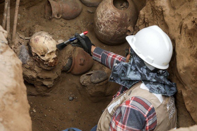 Um arqueólogo limpa um crânio atribuído à cultura pré-inca Chancay, descoberto acidentalmente por trabalhadores que instalavam um gasoduto no distrito de Puente Piedra, em Lima, em 31 de julho de 2025       -  (crédito: CONNIE FRANCE/AFP)