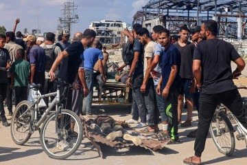 Em Nusseirat, no centro do território palestino, homens carregam os corpos de pessoas mortas enquanto buscavam alimentos -  (crédito: AFP)