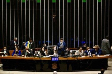 Parlamentares da oposição, com a boca coberta com fita adesiva, ocupam a mesa do presidente durante uma sessão plenária da Câmara em protesto contra a ordem de prisão domiciliar emitida contra o ex-presidente brasileiro Jair Bolsonaro no Congresso Nacional, em Brasília, em 5 de agosto de 2025      Caption  -  (crédito: EVARISTO SA/AFP)