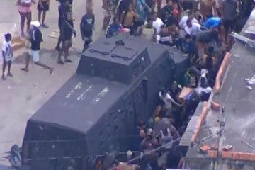 Mesmo com presença de veículo policial, moradores pegam carga de carne roubada no Complexo da Pedreira -  (crédito: Reprodução/Globo)
