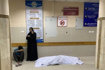 Palestinos ao lado de corpo de vítima de ataque aéreo, em Khan Yunis (sul) 